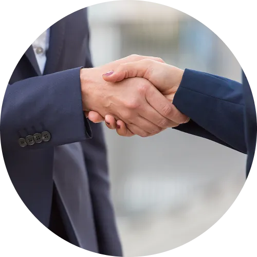 Two people in business attire shaking hands in a professional setting.